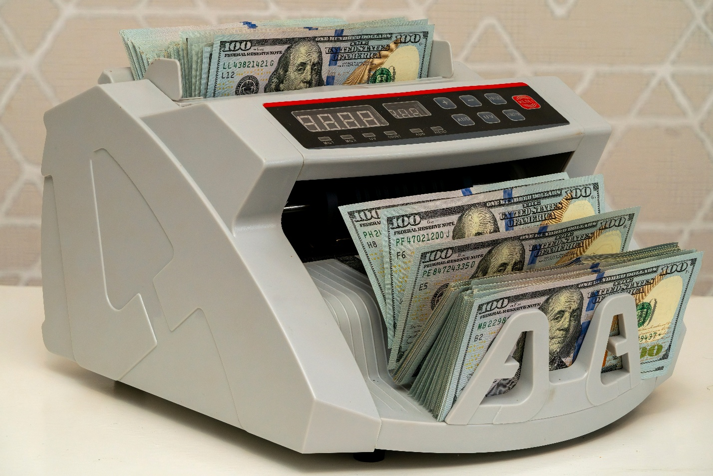 n electronic money counting machine processing a large stack of U.S. twenty-dollar bills.