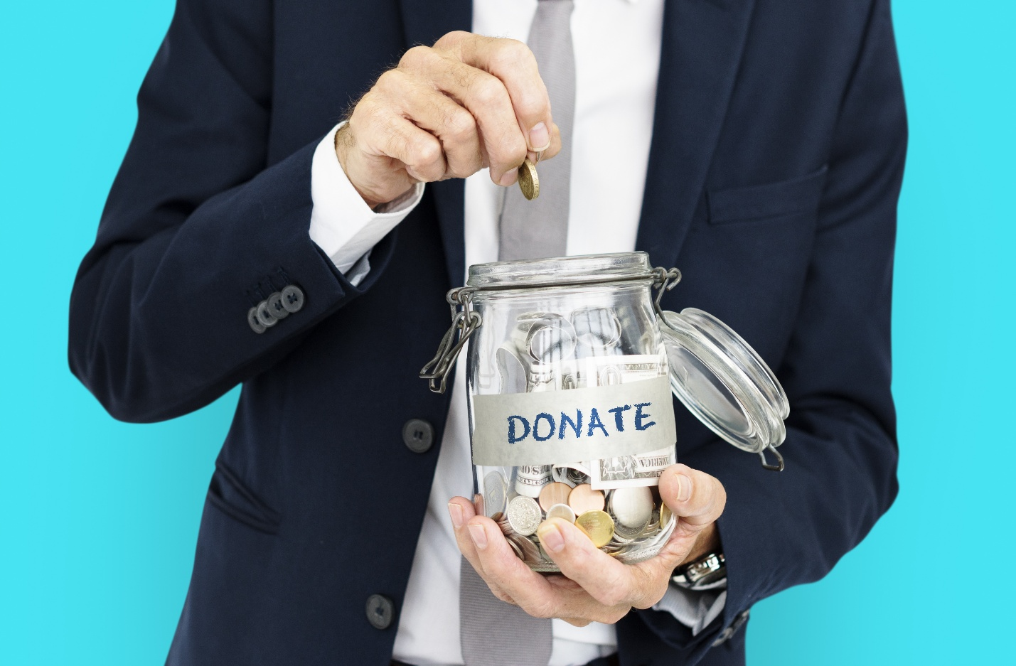 A person in a suit putting a coin into a jar labeled 'DONATE'